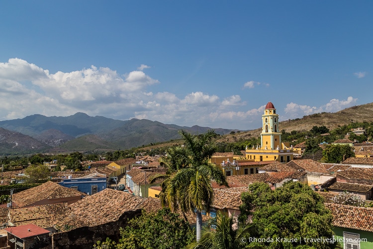 Overlooking the rooftops of Trinidad with a bell tower and mountains in the background.