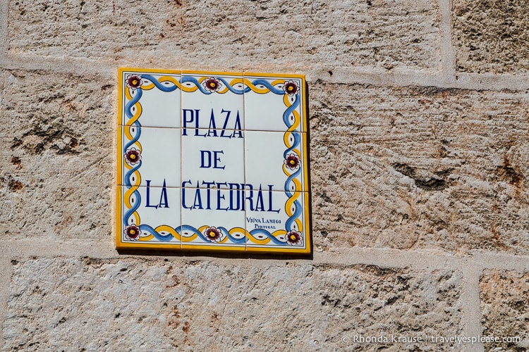 Sign made out of colourful tiles on the side of a building.
