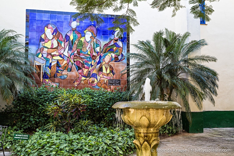 A fountain with plants and a mural.