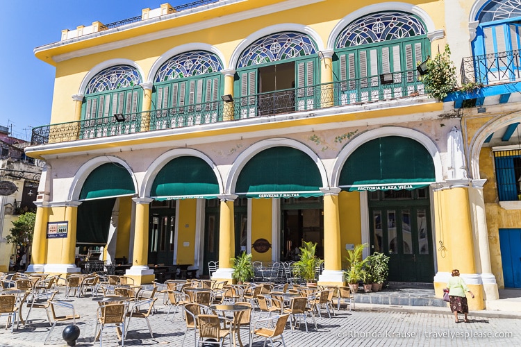 Yellow building with table and chairs out front in the plaza.