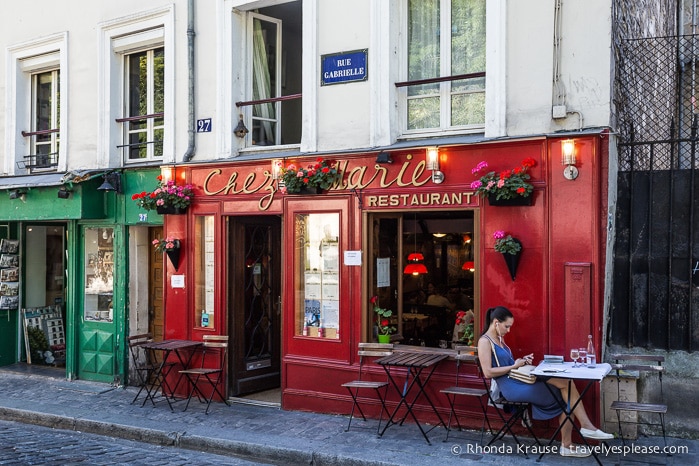 Woman sitting outside a cafe with a red wall.