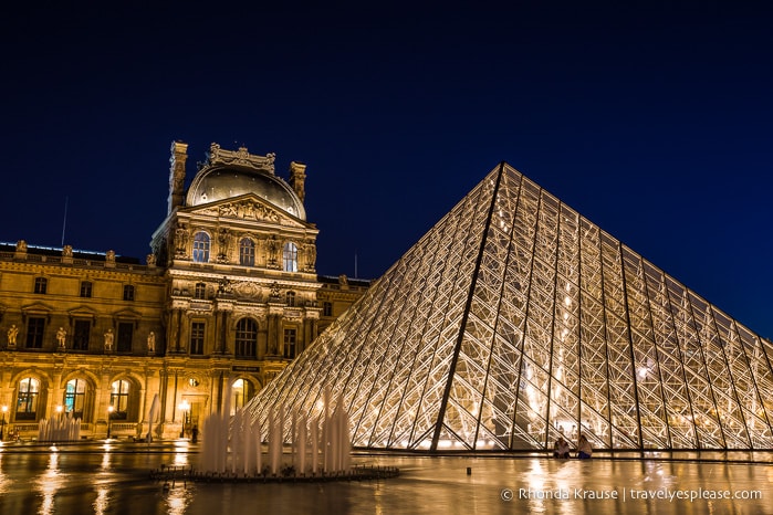 Exterior of the Louvre illuminated at night.