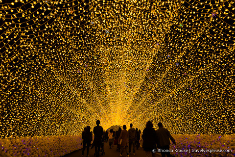 People walking through a tunnel of yellow lights at Nabana no Sato