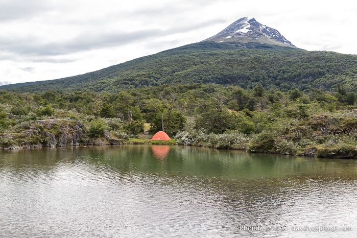 Tent on the shore of Ovando River with a mountain in the background.