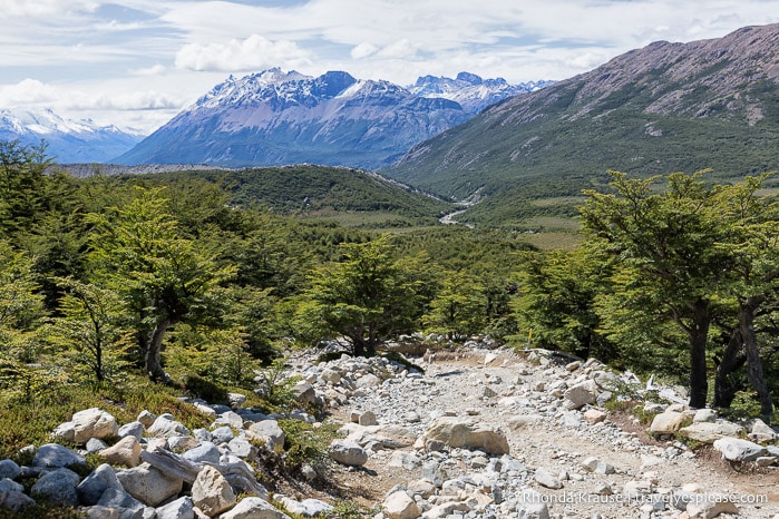 Rock covered trail with mountains in the background.