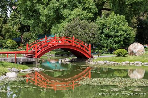 Red arched bridge crossing the pond.