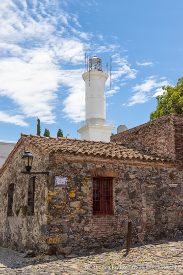 Stone house with the Colonia del Sacramento lighthouse in the background.