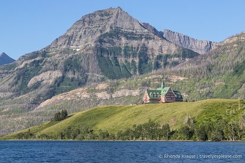 Prince of Wales Hotel on a bluff overlooking Middle Waterton Lake with mountains in the background.