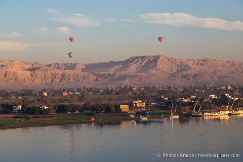Hot air balloons flying over the west bank of Luxor at sunrise.