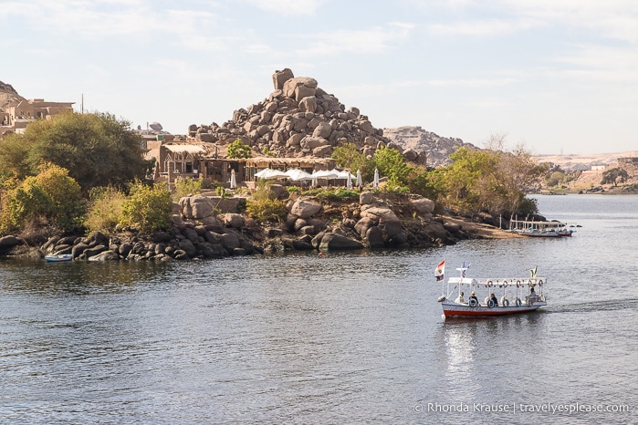 Small shuttle boat on the Nile in front of a rocky hill.