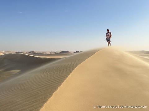Person standing on a sand dune in the desert.