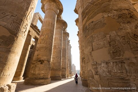 Woman walking between the columns of Karnak Temple.