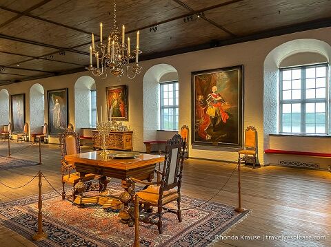 Table and paintings in a large room inside Akershus Fortress.