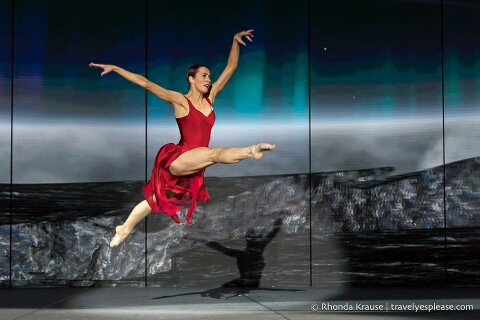 Dancer in a red dress leaping during a performance.