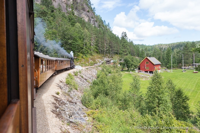 Setesdal Vintage Railway going around a bend beside a red building.