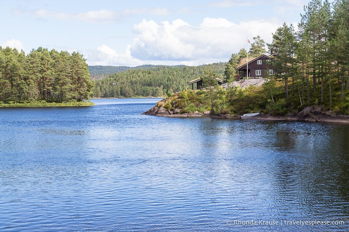 Brown house in the forest overlooking a lake.