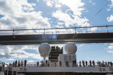People watching from the deck of a cruise ship as it goes under Hardanger Bridge.