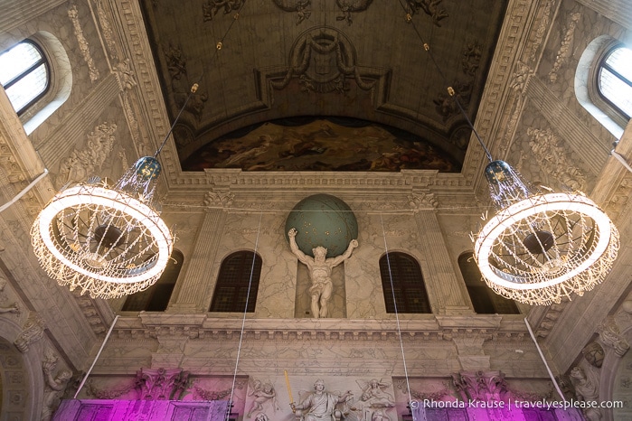 Chandeliers and a statue of Atlas inside the Royal Palace of Amsterdam.