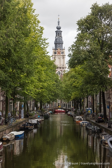 Church tower at the end of a canal lined with boats. 
