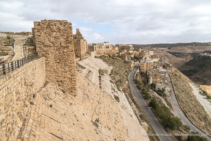 Wall of Kerak Castle on a hillside overlooking a road.