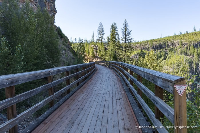 Wooden bridge beside a canyon wall.