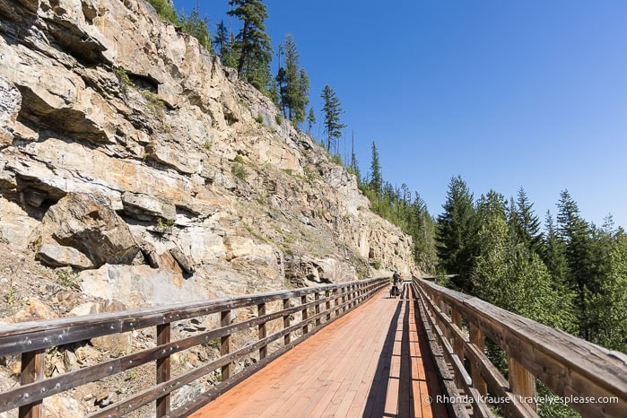Wooden bridge beside a rocky canyon wall.