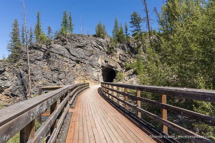 Wooden bridge leading towards a rock tunnel.