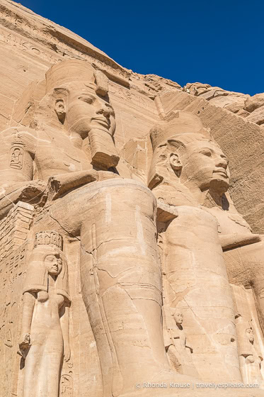 Looking up at two colossi of Ramesses the Great and the small statues at their feet.