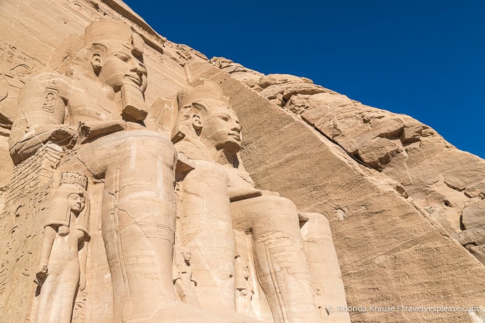 Looking up at two colossi of Ramesses the Great and the small statues at their feet.