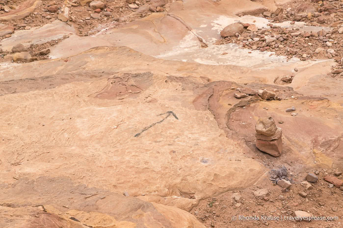 Painted arrow on the flat, rocky surface of the trail.