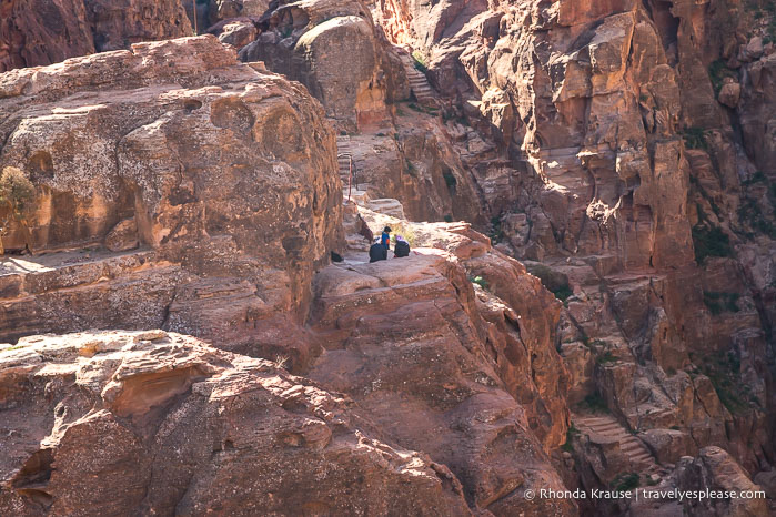 People sitting on rocks at another viewpoint across the Siq.