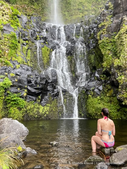 Sitting on a rock in front of a waterfall. 