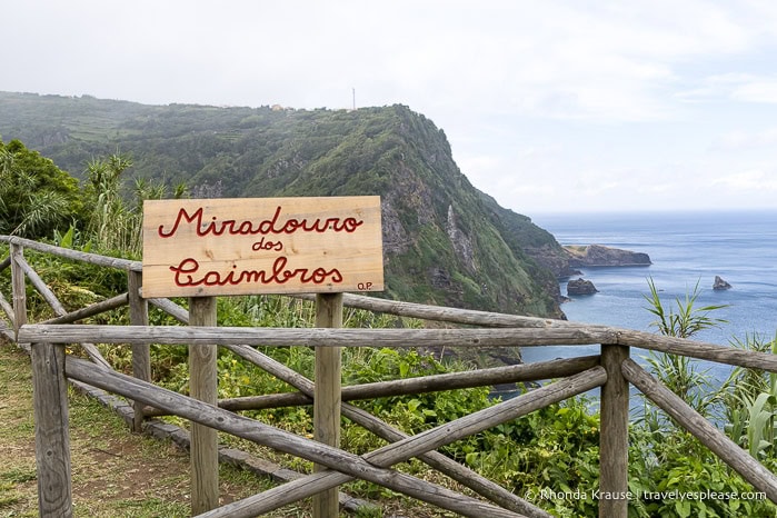 Sign at a coastal viewpoint with cliffs in the background. 